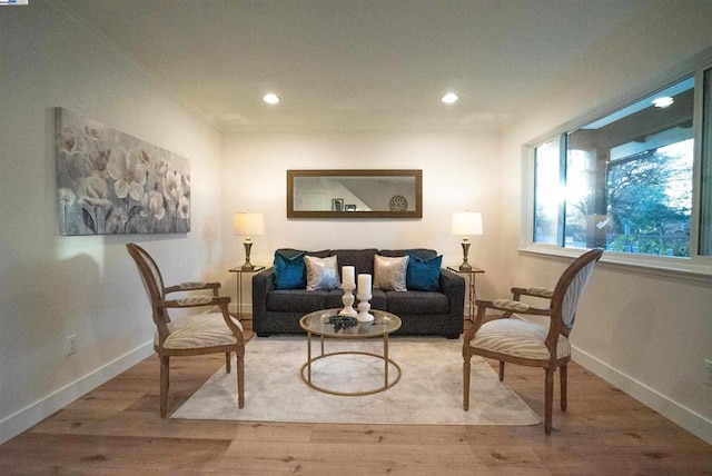 living area with crown molding and light hardwood / wood-style floors