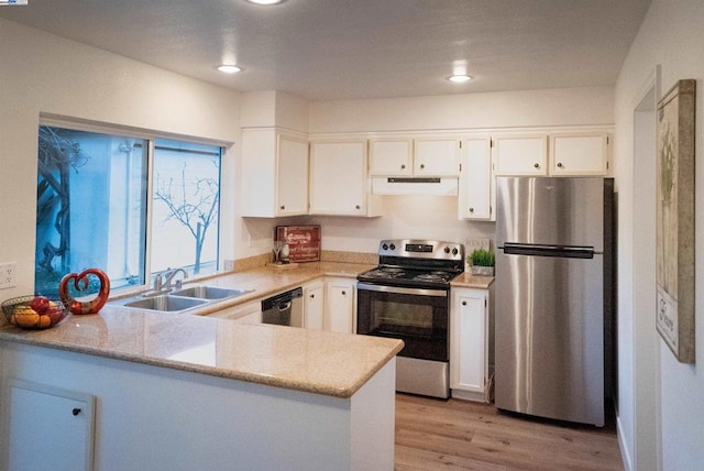 kitchen featuring appliances with stainless steel finishes, white cabinetry, light hardwood / wood-style floors, sink, and kitchen peninsula