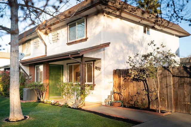 view of front of property featuring a front lawn and central AC