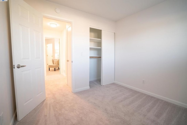 unfurnished bedroom with a closet and light carpet