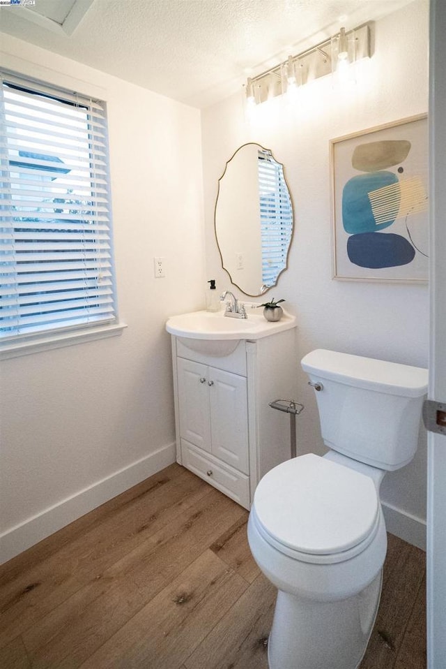 bathroom with toilet, vanity, a textured ceiling, and hardwood / wood-style floors