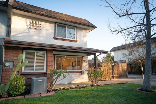 rear view of house with central AC unit, a lawn, and a patio