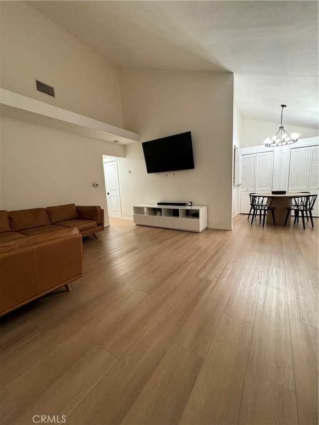 living room with high vaulted ceiling, an inviting chandelier, and hardwood / wood-style flooring