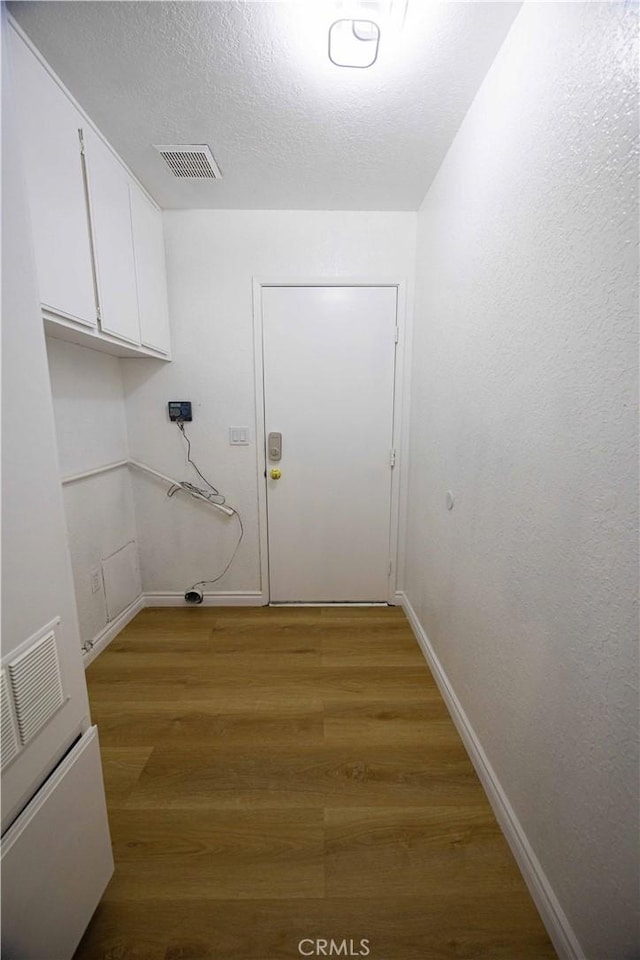 clothes washing area featuring cabinets and wood-type flooring