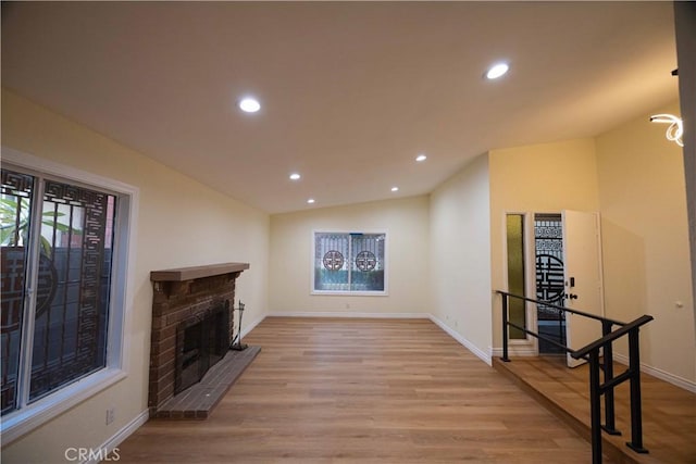 living room with lofted ceiling, a fireplace, and light hardwood / wood-style floors