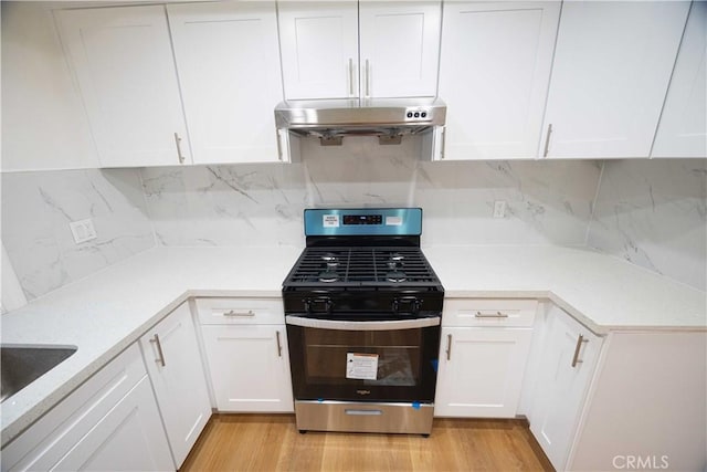 kitchen with white cabinets, decorative backsplash, stainless steel range with gas stovetop, and light hardwood / wood-style flooring