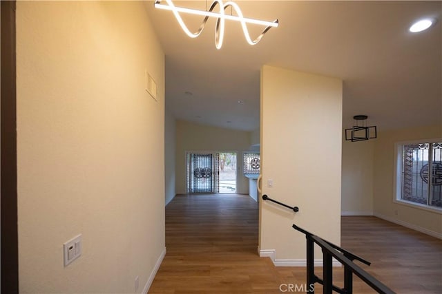 hallway featuring vaulted ceiling, a notable chandelier, and hardwood / wood-style floors