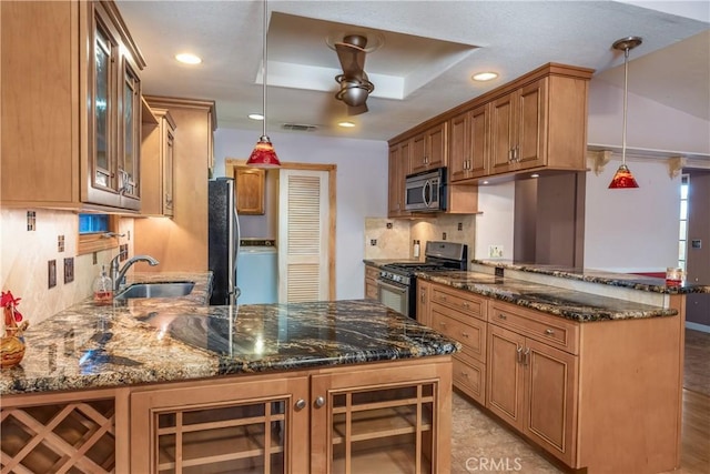 kitchen with pendant lighting, tasteful backsplash, dark stone counters, kitchen peninsula, and stainless steel appliances