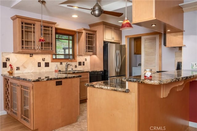 kitchen with sink, stainless steel fridge, decorative light fixtures, kitchen peninsula, and dark stone counters