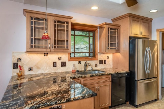 kitchen featuring sink, dark stone countertops, stainless steel refrigerator, black dishwasher, and decorative backsplash