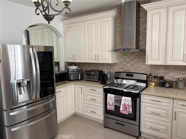 kitchen featuring wall chimney exhaust hood, tasteful backsplash, light tile patterned floors, a notable chandelier, and stainless steel appliances