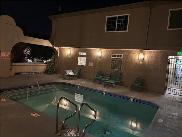 pool at night with a patio area