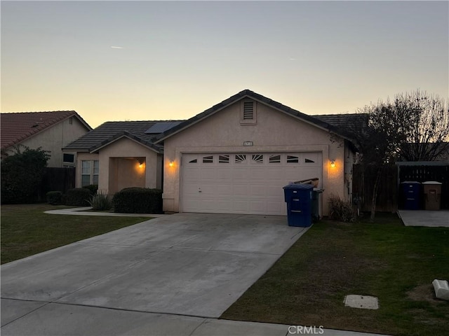 single story home with a garage, a lawn, and solar panels