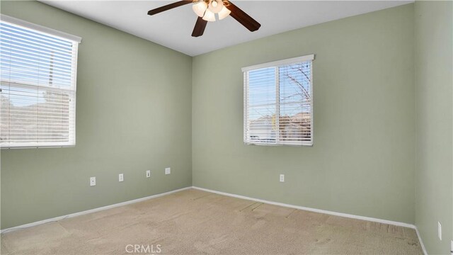 carpeted spare room featuring ceiling fan