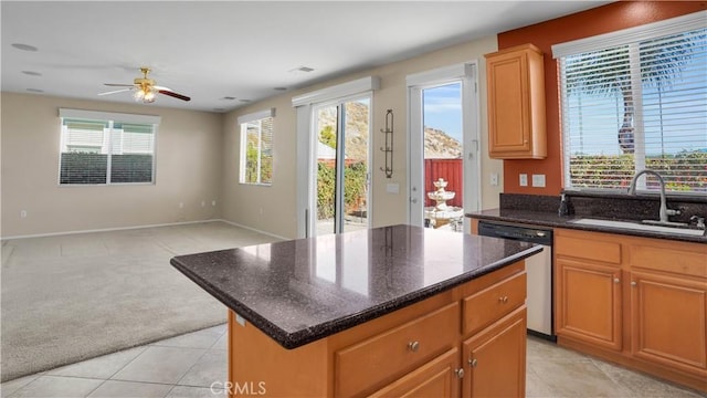 kitchen featuring sink, dishwasher, a center island, light colored carpet, and dark stone counters