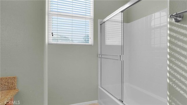 bathroom featuring enclosed tub / shower combo and a wealth of natural light