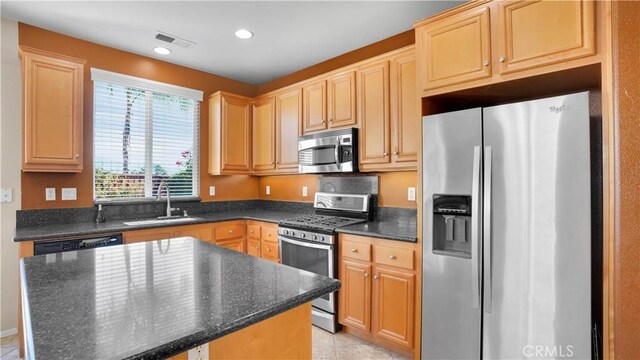 kitchen featuring sink, dark stone countertops, light tile patterned floors, a kitchen island, and stainless steel appliances