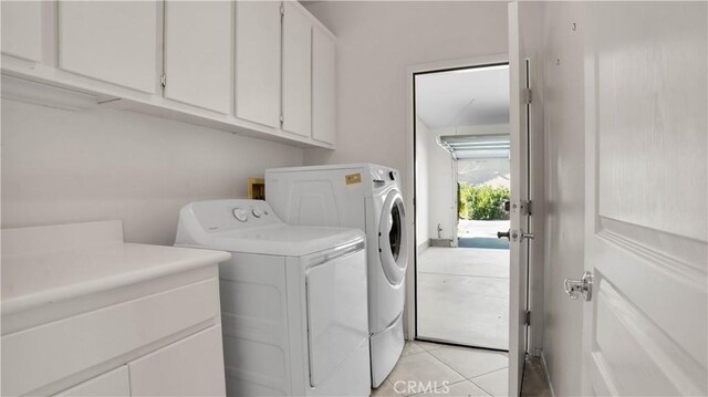 washroom featuring cabinets, washer and dryer, and light tile patterned floors