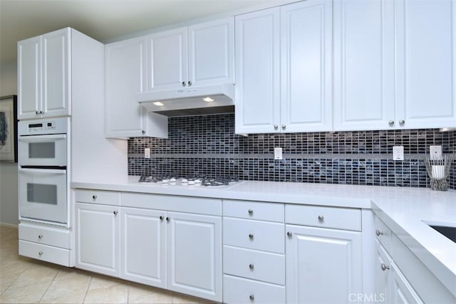 kitchen featuring light tile patterned floors, white cabinetry, tasteful backsplash, and white appliances