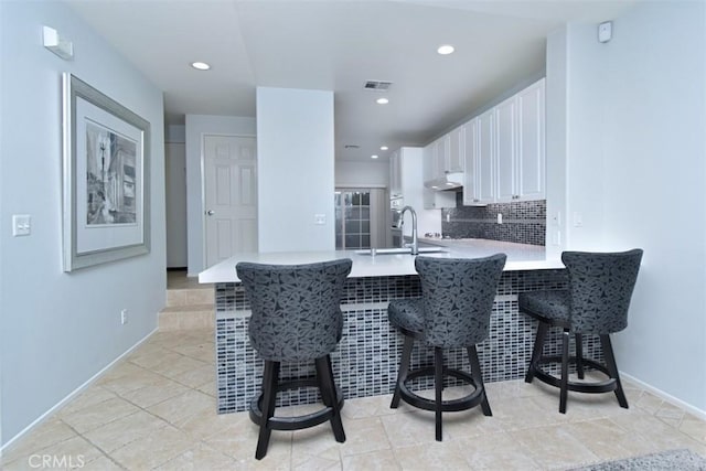 kitchen with a kitchen breakfast bar, white cabinets, kitchen peninsula, and sink