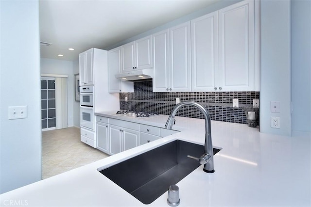 kitchen featuring sink, white cabinetry, stainless steel gas stovetop, and tasteful backsplash