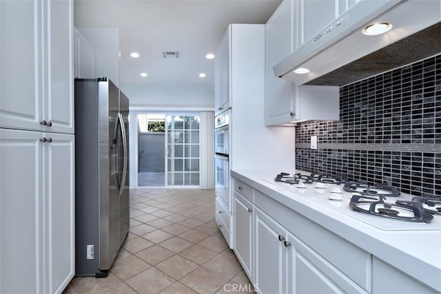 kitchen featuring white appliances, white cabinets, tasteful backsplash, light tile patterned flooring, and range hood