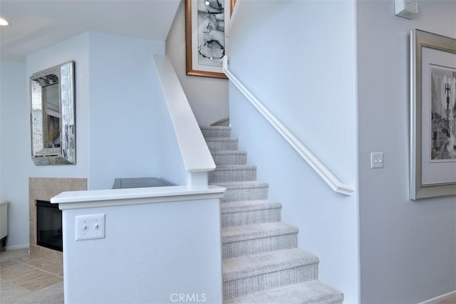 staircase with a tiled fireplace and tile patterned flooring