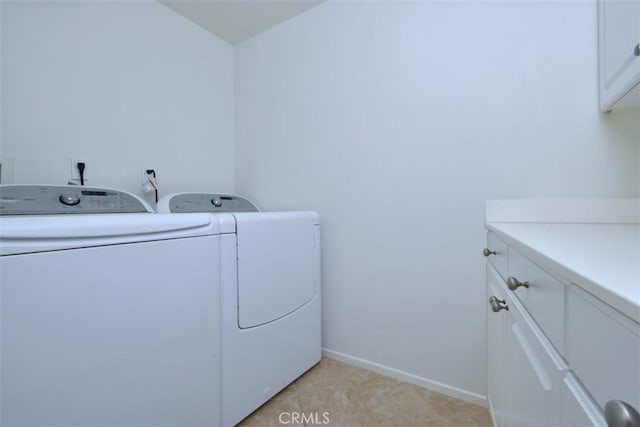 clothes washing area with washing machine and dryer, cabinets, and light tile patterned flooring