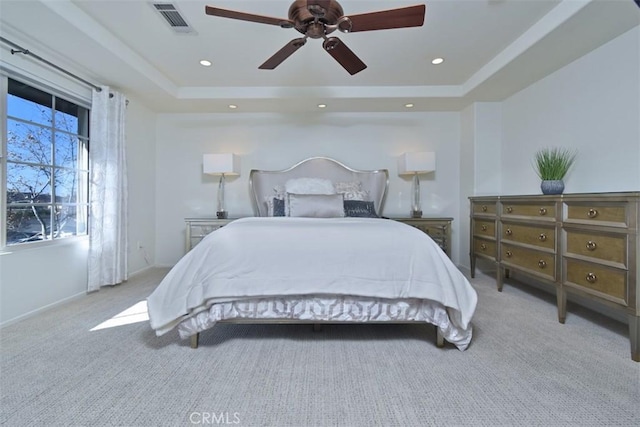 carpeted bedroom with ceiling fan and a tray ceiling