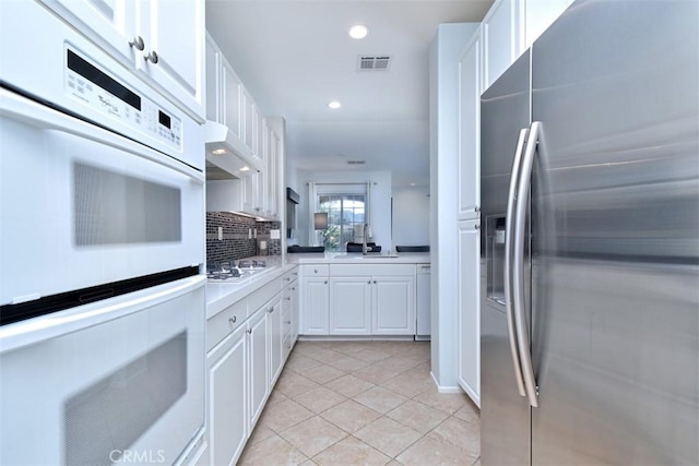 kitchen featuring light tile patterned floors, white cabinetry, backsplash, white appliances, and sink