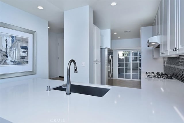 kitchen with white gas stovetop, white cabinetry, tasteful backsplash, sink, and stainless steel fridge with ice dispenser