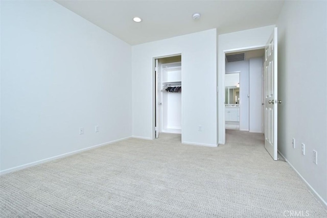 unfurnished bedroom featuring light carpet, a closet, and a spacious closet