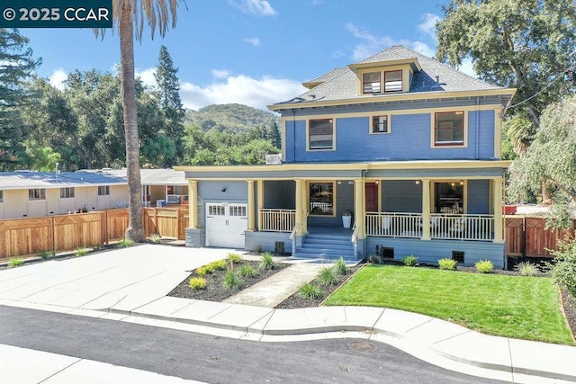 front facade featuring a front lawn, a mountain view, covered porch, and a garage