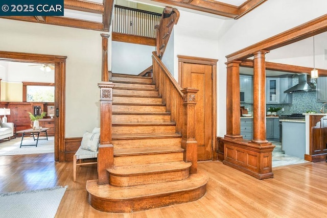 stairs featuring ceiling fan, hardwood / wood-style flooring, and ornate columns