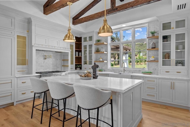 kitchen with sink, a breakfast bar, white cabinetry, tasteful backsplash, and a kitchen island