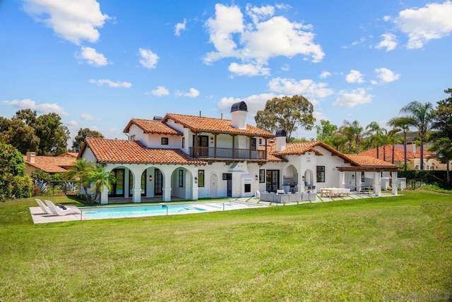 back of house with a balcony, an outdoor hangout area, a patio area, and a lawn