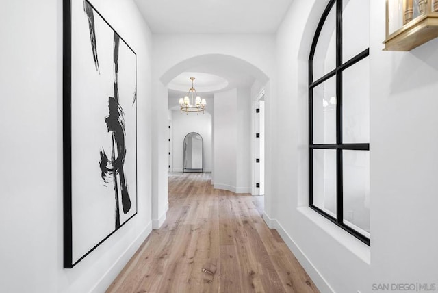 hallway with light hardwood / wood-style flooring and a notable chandelier