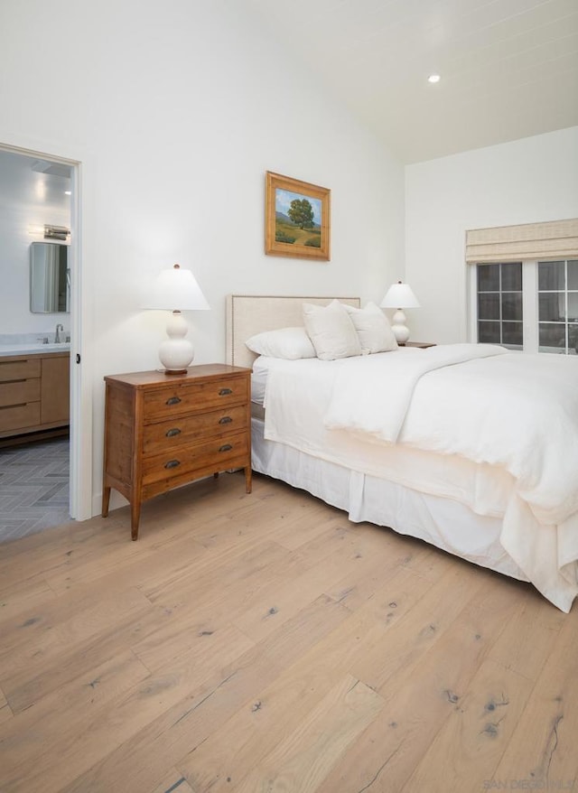 bedroom with light wood-type flooring, sink, and connected bathroom