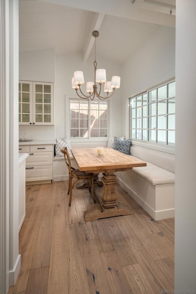 dining room with a chandelier, breakfast area, lofted ceiling with beams, and light hardwood / wood-style flooring