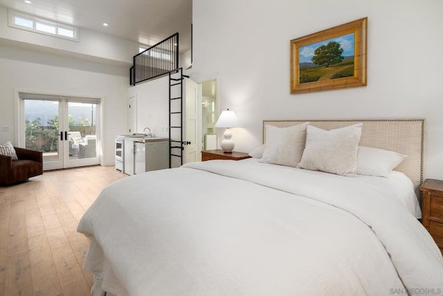 bedroom featuring french doors, light hardwood / wood-style flooring, access to outside, and multiple windows