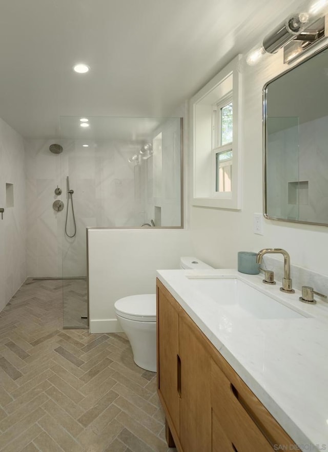 bathroom featuring a tile shower, vanity, and toilet