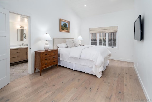 bedroom with light wood-type flooring, connected bathroom, vaulted ceiling, and sink