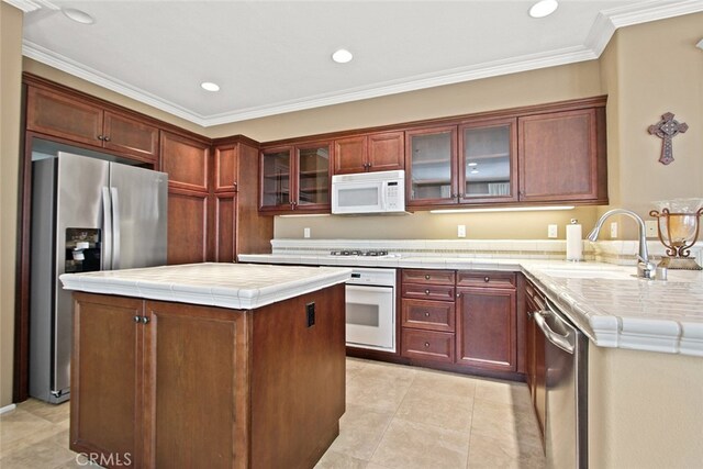 kitchen with sink, crown molding, tile countertops, a center island, and appliances with stainless steel finishes