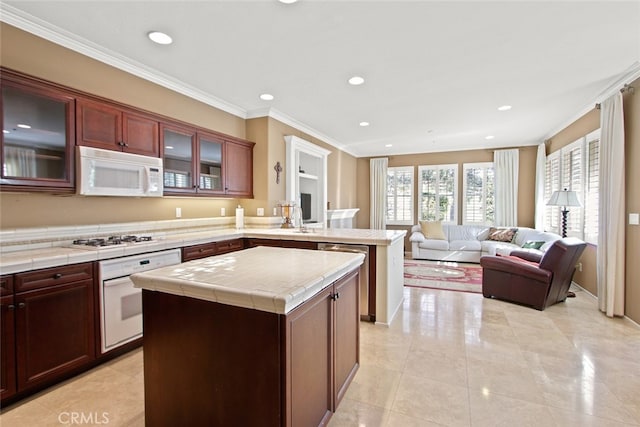 kitchen with light tile patterned flooring, ornamental molding, a center island, tile counters, and white appliances