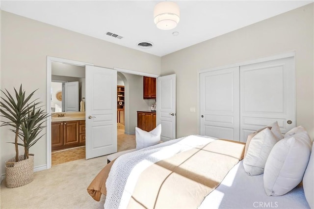 carpeted bedroom featuring ensuite bath and a closet