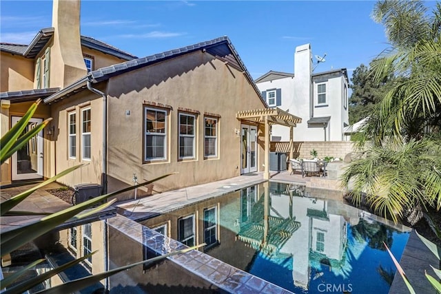 rear view of property with a patio and a pergola