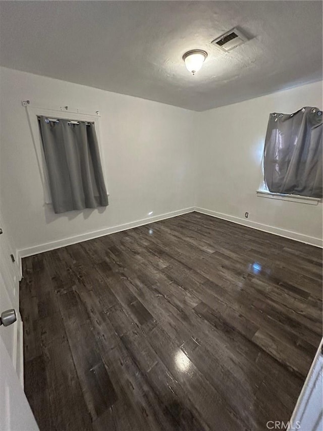 empty room with dark hardwood / wood-style flooring and a textured ceiling