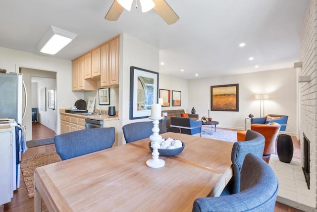 dining space with ceiling fan, a fireplace, and light hardwood / wood-style flooring