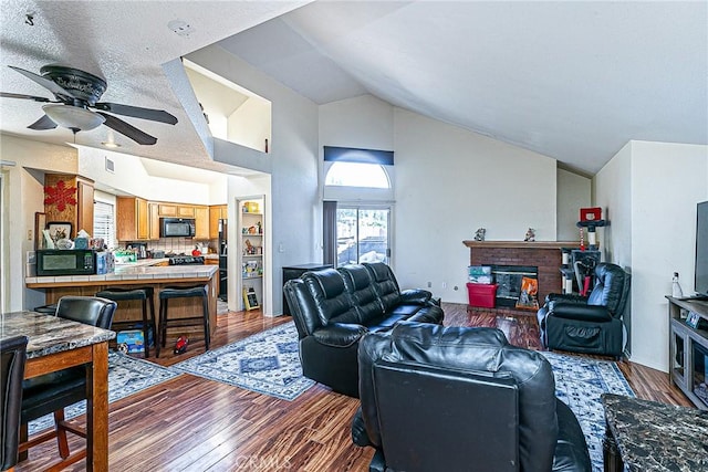 living room with a fireplace, hardwood / wood-style floors, a textured ceiling, and vaulted ceiling