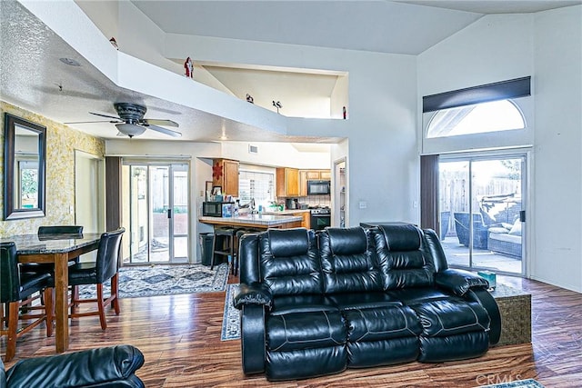 living room with ceiling fan, dark hardwood / wood-style flooring, a textured ceiling, and lofted ceiling